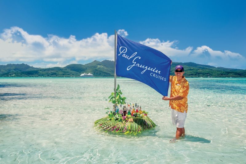 Paul Gauguin flag and crew member on a beach PR image